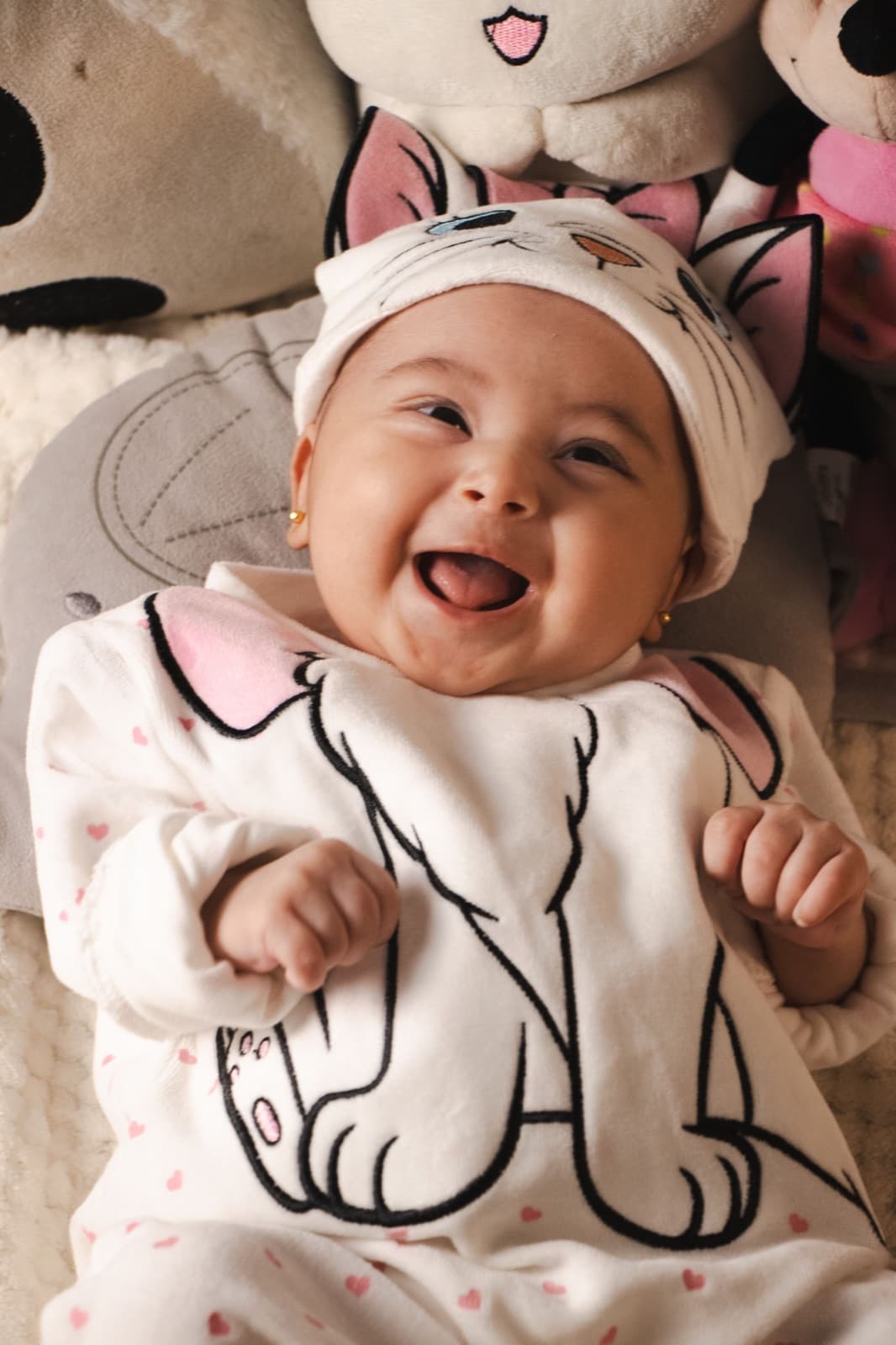 Bebê sorrindo deitado em um ambiente acolhedor