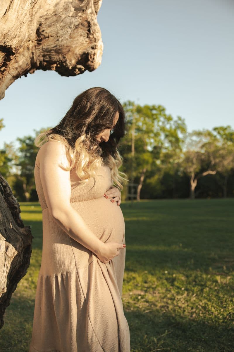 Gestante acariciando a barriga em um parque