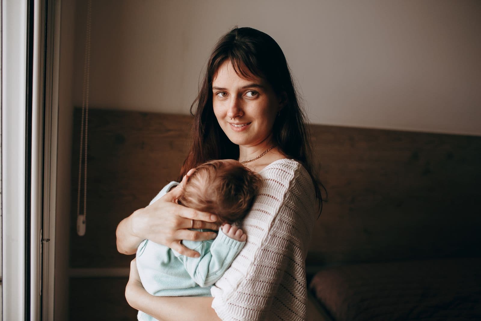 Mãe segurando seu bebê junto à janela