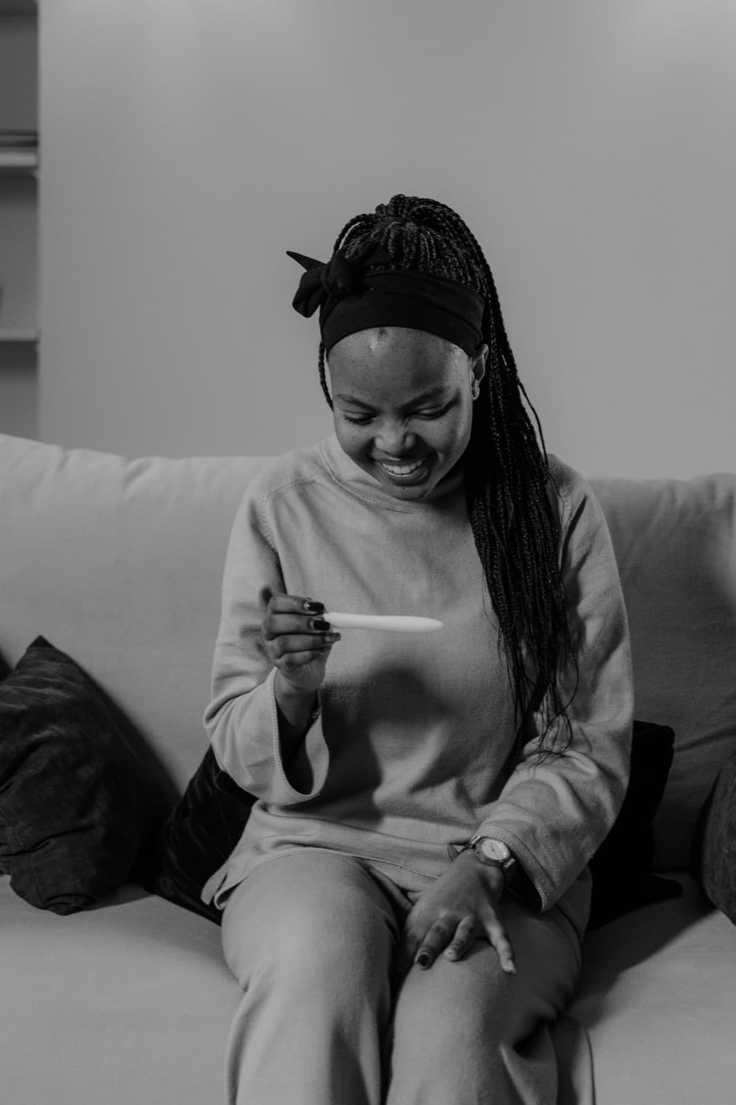 Mulher sorrindo ao olhar um teste de gravidez