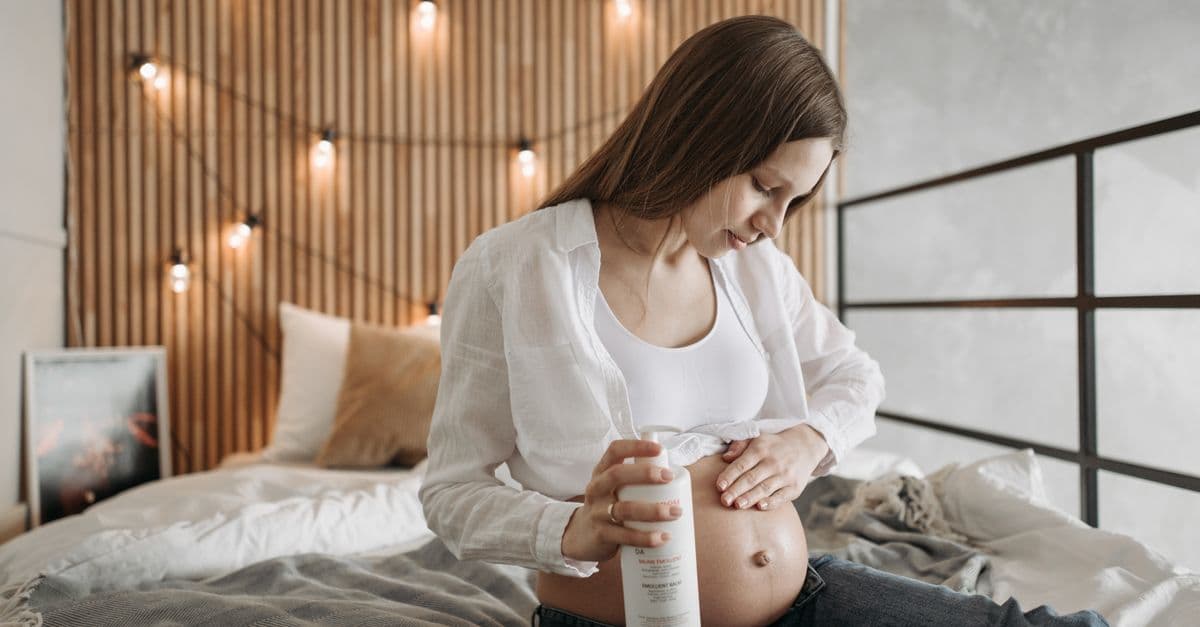 Gestante aplica hidratante suavemente na barriga