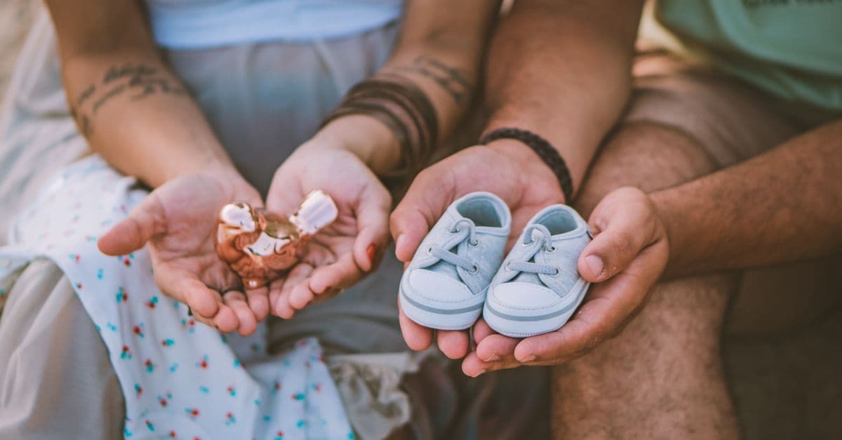 Casal segurando um par de sapatinhos de bebê nas mãos