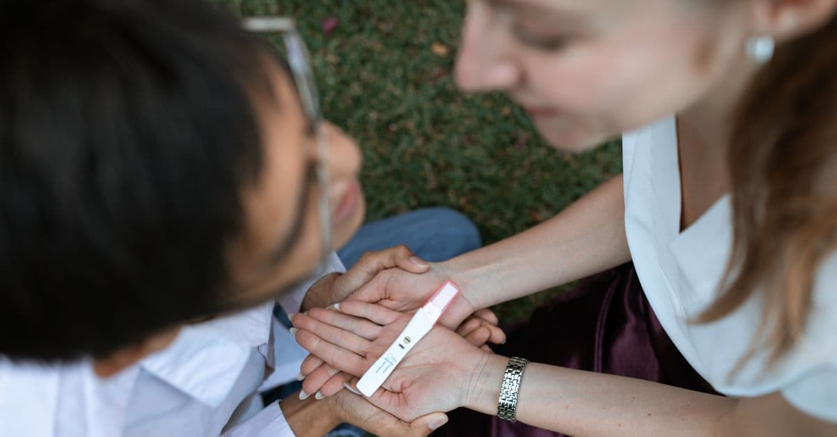 Duas pessoas acolhem uma mulher que segura um teste de gravidez