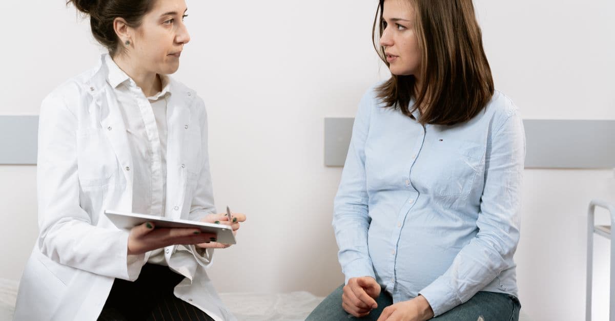 Gestante conversando com uma profissional de saúde durante uma consulta