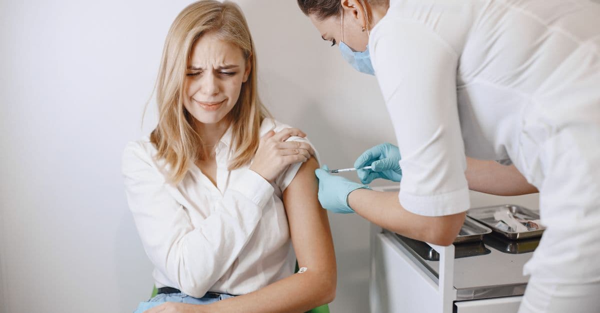 Profissional de saúde aplicando uma vacina no braço de uma mulher